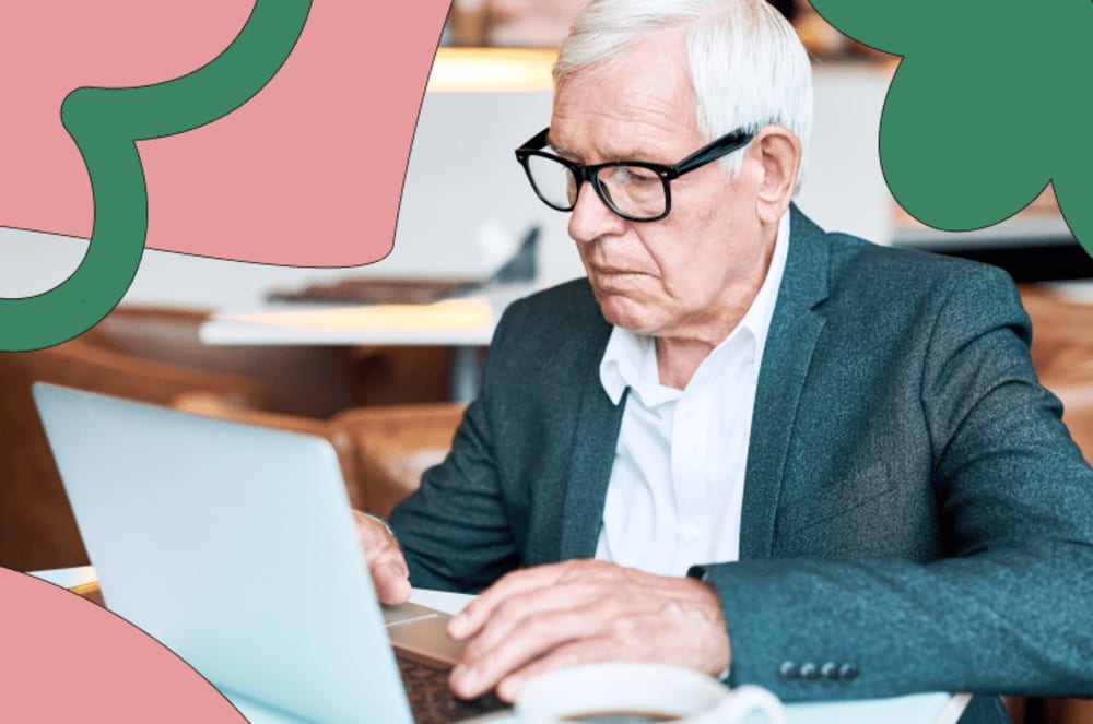 Older man with glasses sitting down in front of a laptop