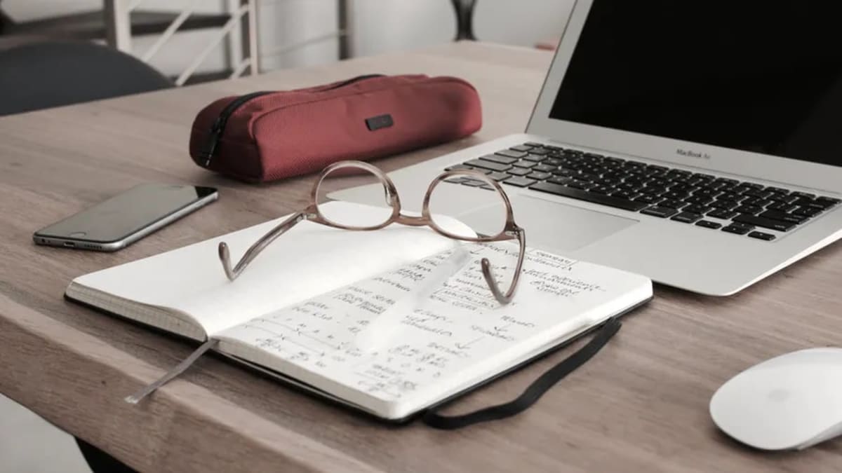 Glasses, notebook, and pencil case left in front of open laptop to symbolise developing a growth mindset