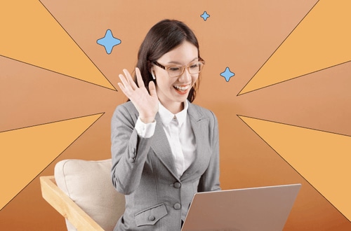 Woman sitting down in front of a laptop smiling and waving