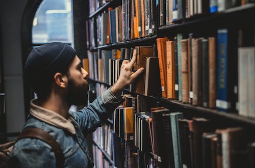 Man in a library reaching for a book, symbolising right skilling