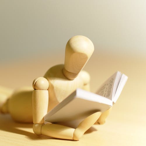 Wooden figurine reading a book to symbolise the learn, unlearn, relearn cycle