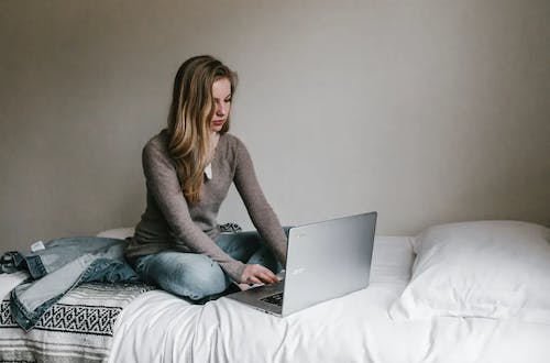Woman in a grey shirt working on her laptop and staying focused