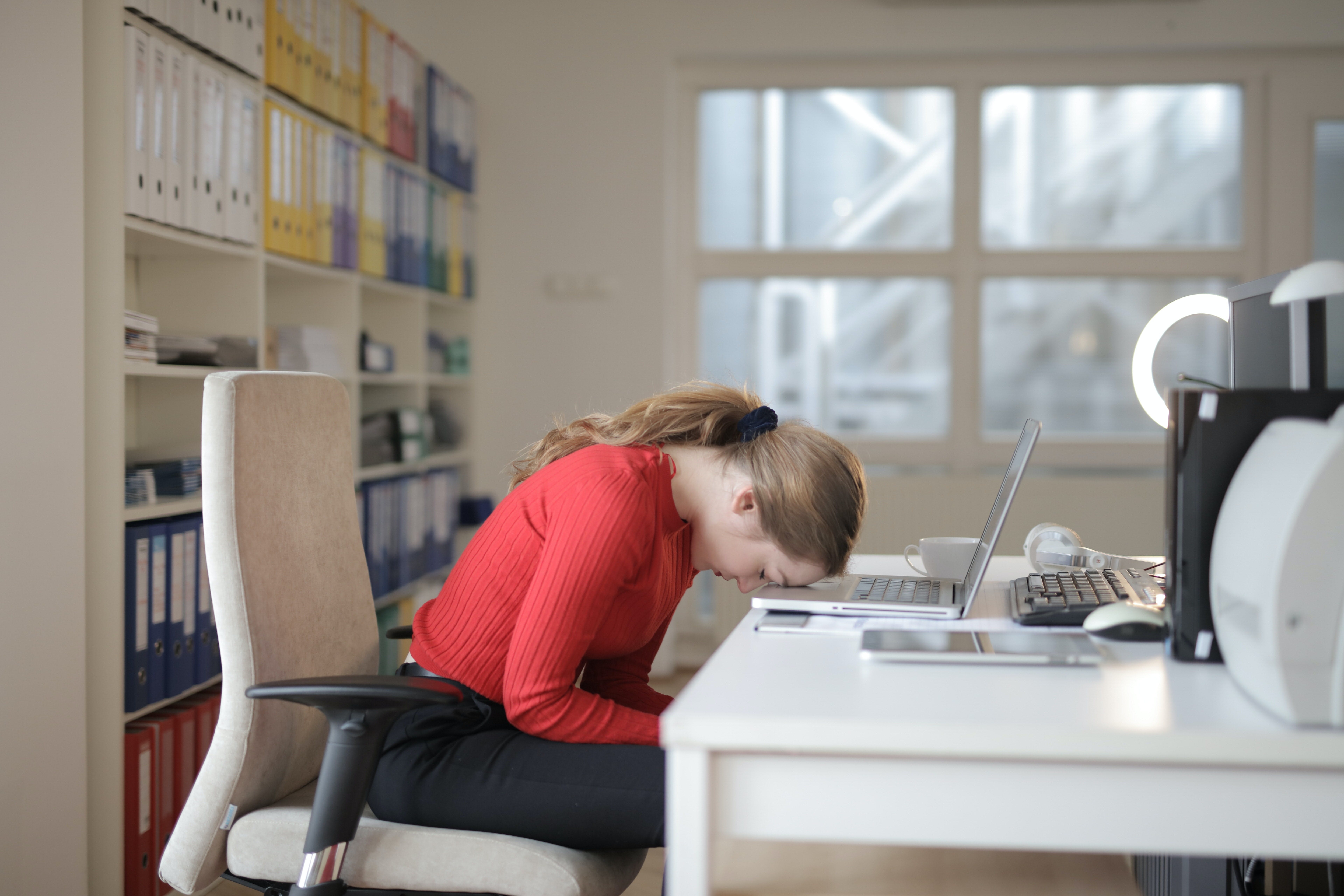 Woman sitting at a desk looking very tired