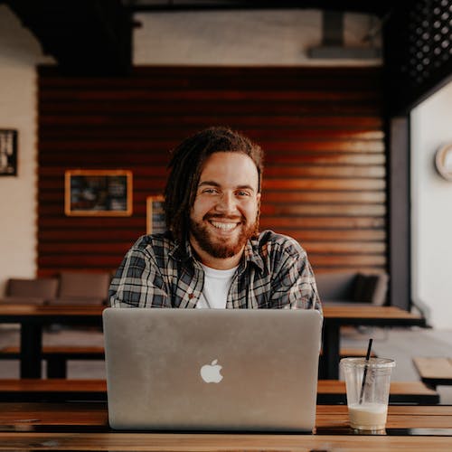 Man sitting behind a laptop smiling (front on view)