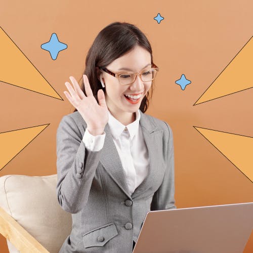 Woman sitting down in front of a laptop smiling and waving