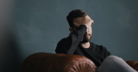 Man sitting on a couch with his head in his hands