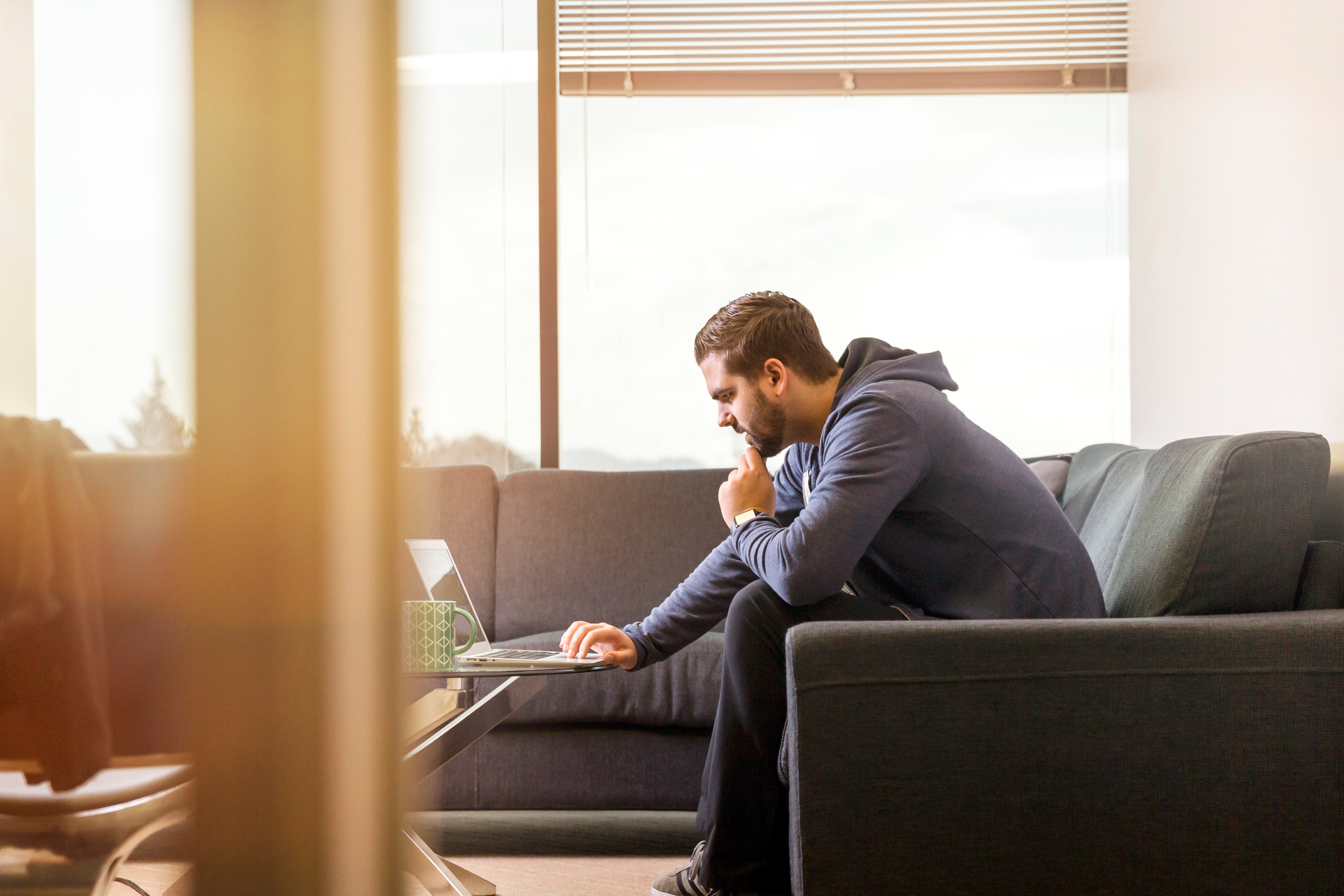 Man sitting on his couch looking at a laptop