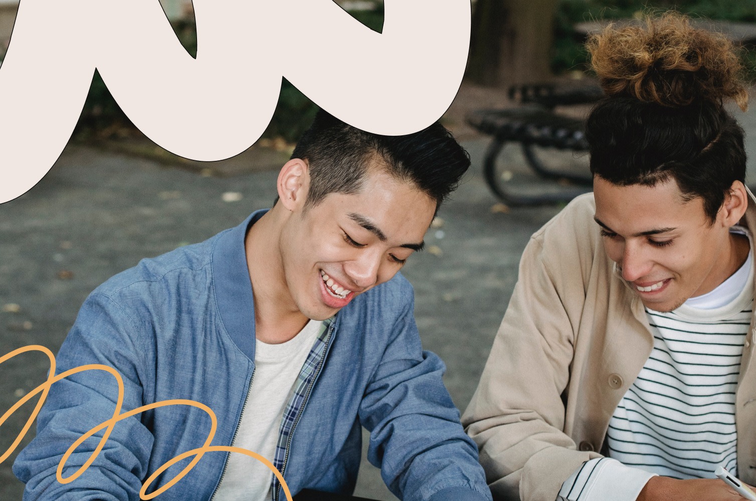 Two male friends sitting on a bench and writing in a notepad